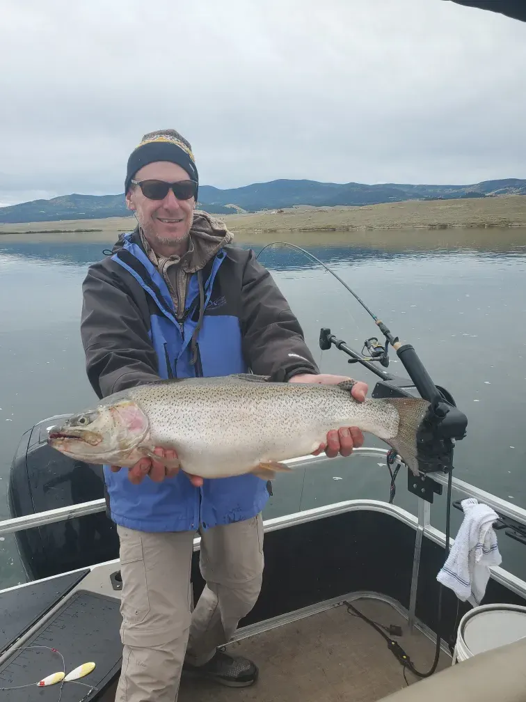 A guest with an outsized rainbow trout caught from the pontoon