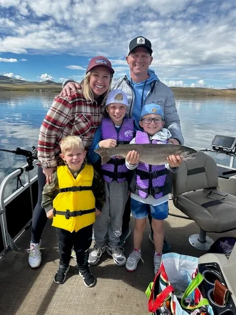 A family aboard the pontoon with a rainbow trout one of the children is holding