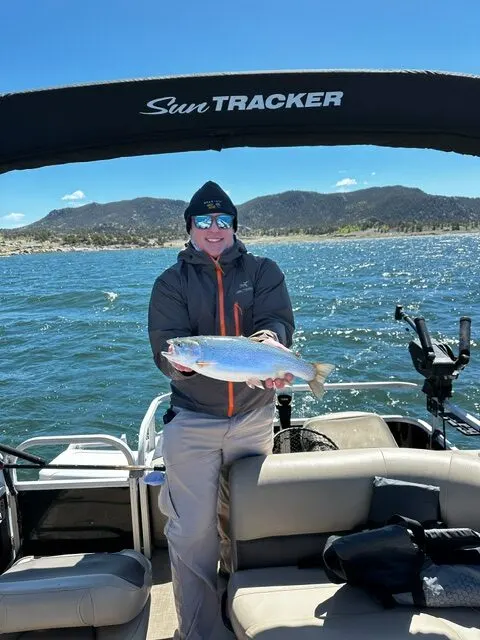 A guest holding a rainbow trout with the South Park hills behind